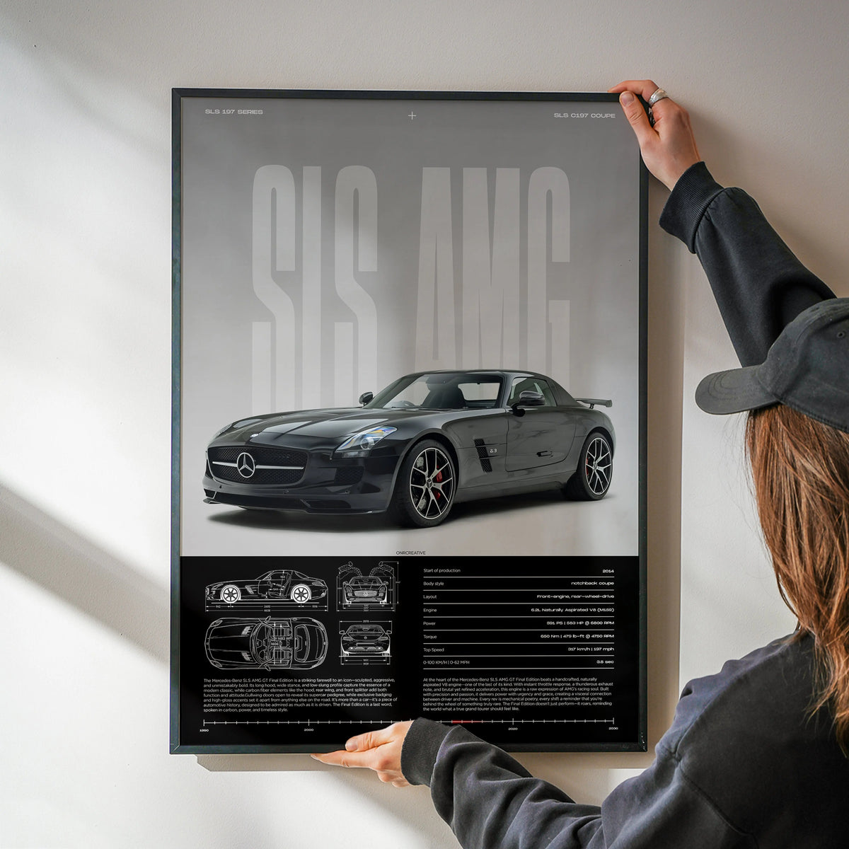 Person hanging framed Mercedes-Benz SLS AMG GT poster on white wall, modern AMG wall art featuring black SLS AMG GT coupe with technical blueprint design