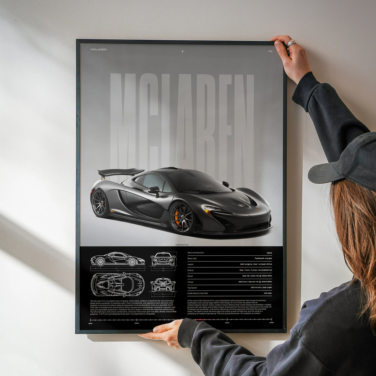 Large framed McLaren P1 poster being mounted on wall showcasing hybrid supercar design
