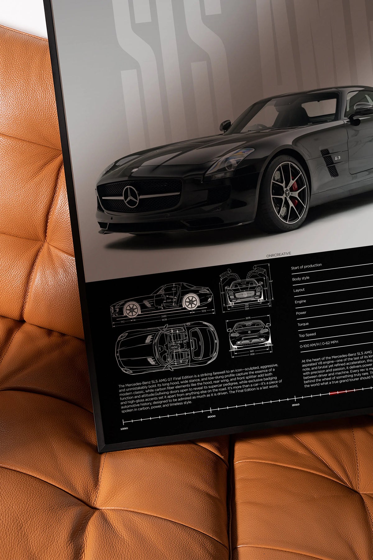 Close-up of Mercedes-Benz SLS AMG GT framed poster on brown leather chair showing black coupe artwork, technical blueprint diagrams and premium matte print detail