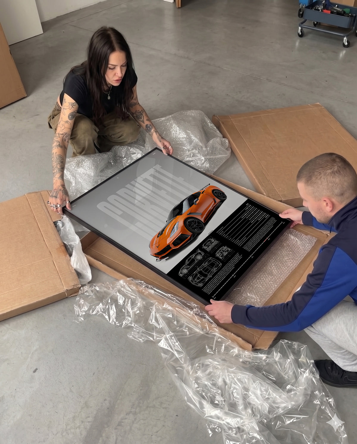 Unboxing a framed Chevrolet Corvette ZR1 poster with protective packaging, bubble wrap, and cardboard box