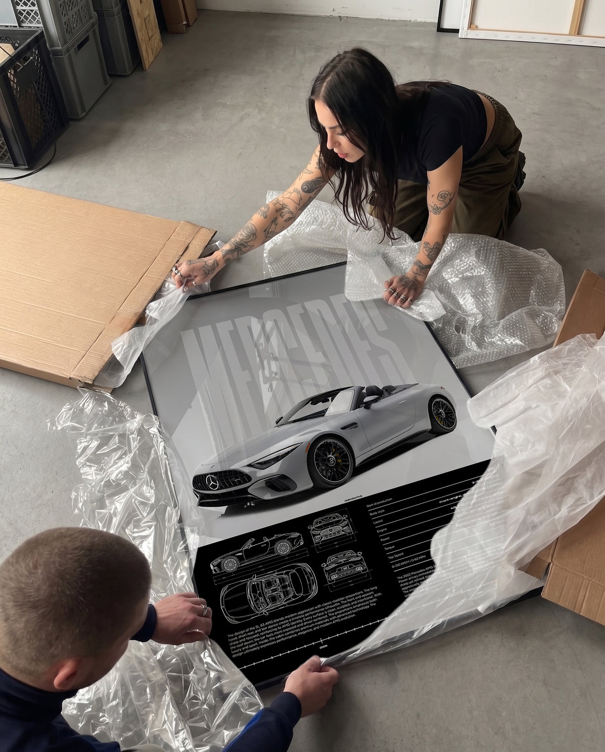 Unboxing a framed Mercedes-AMG SL 63 poster with protective packaging, bubble wrap, cardboard box, and black frame