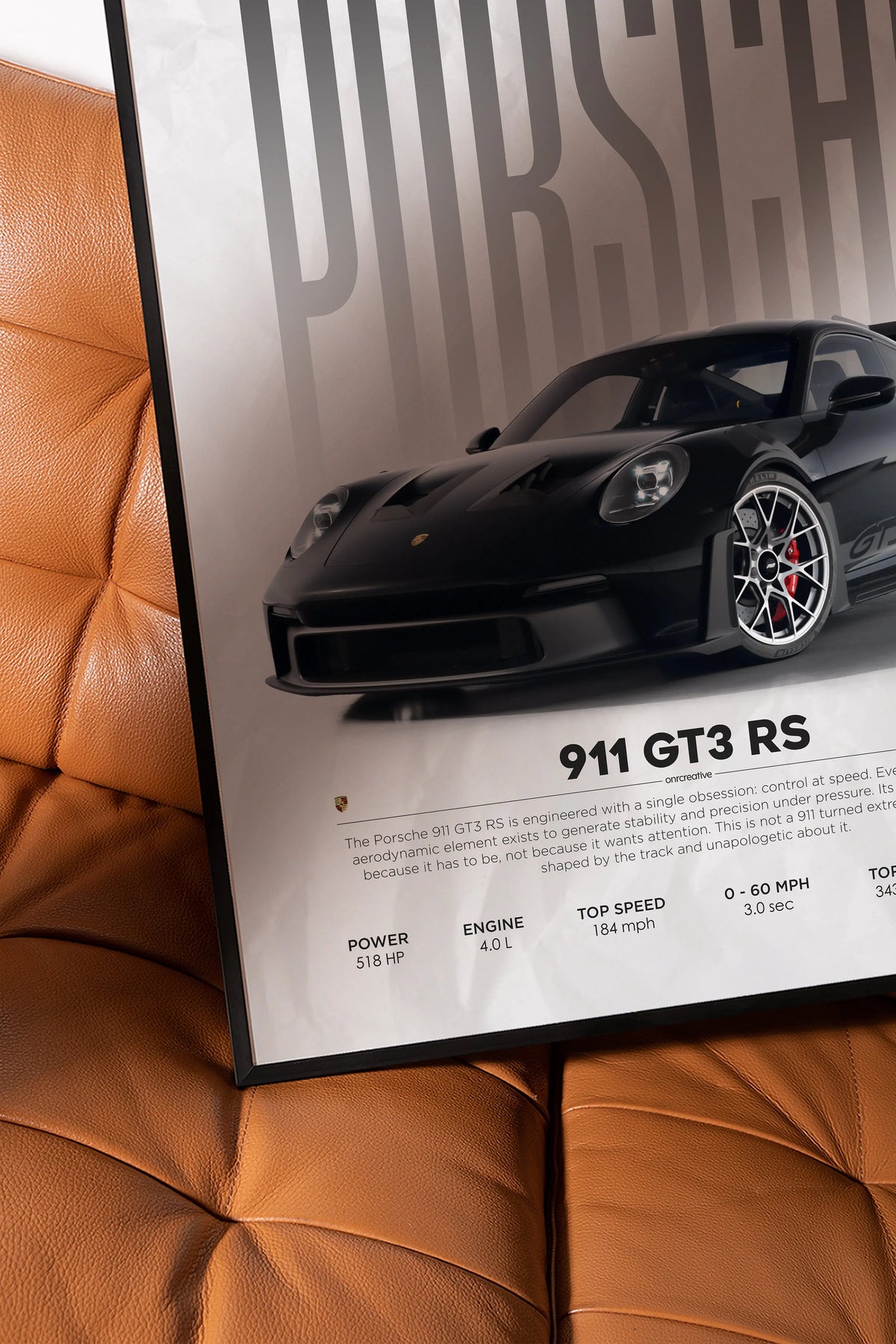 Close up of Porsche 911 GT3 RS wall art resting on brown leather chair, showing premium matte print quality and detailed car specs layout