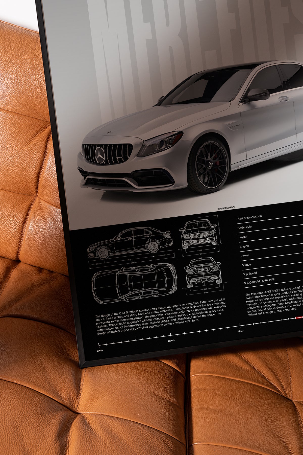 Framed Mercedes-AMG C 63 S W205 poster displayed on a brown leather chair, showing silver sedan artwork, blueprint details, and technical data section